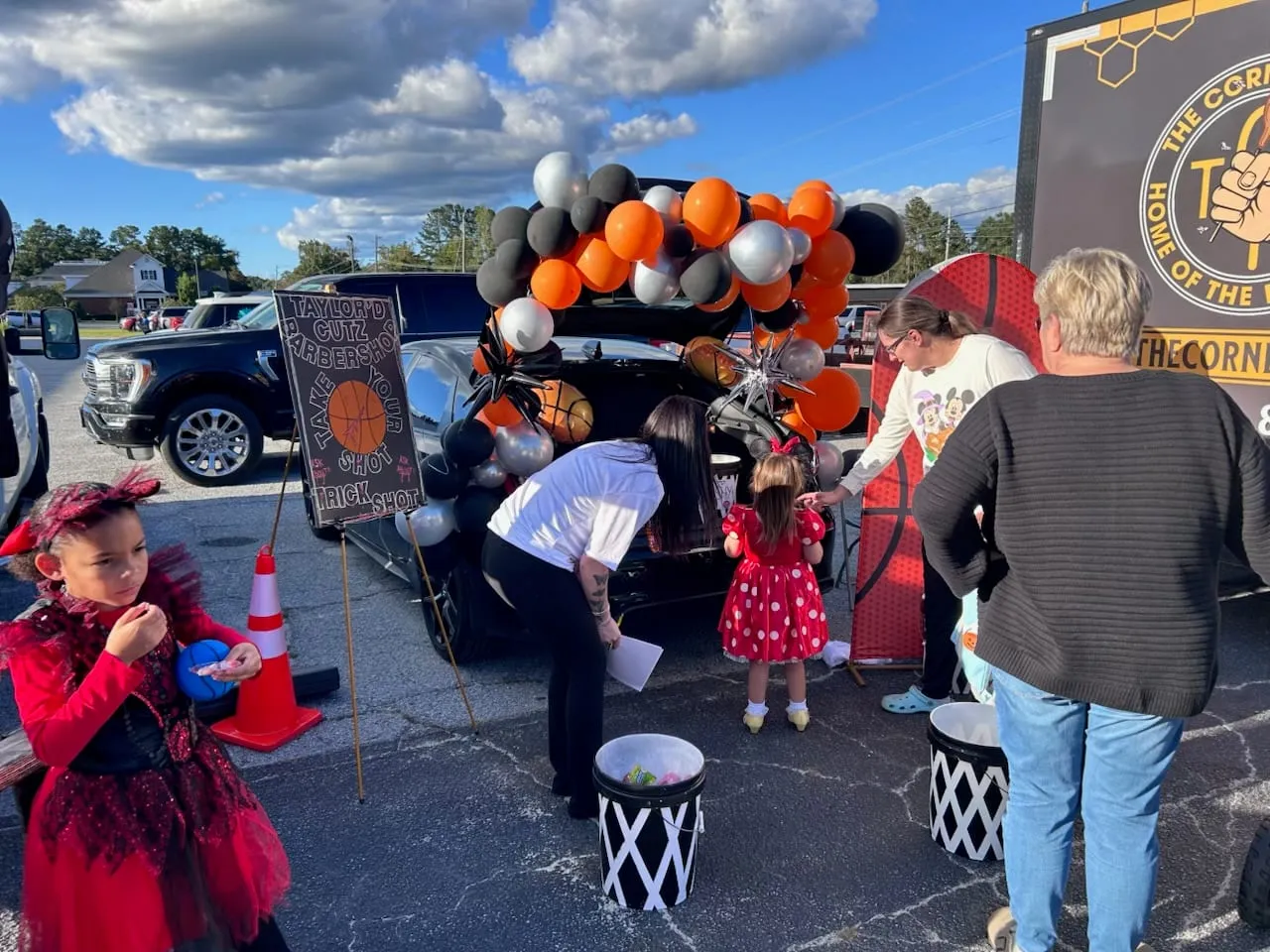 Children in costumes and adults at the balloon-decorated trunk on a sunny day