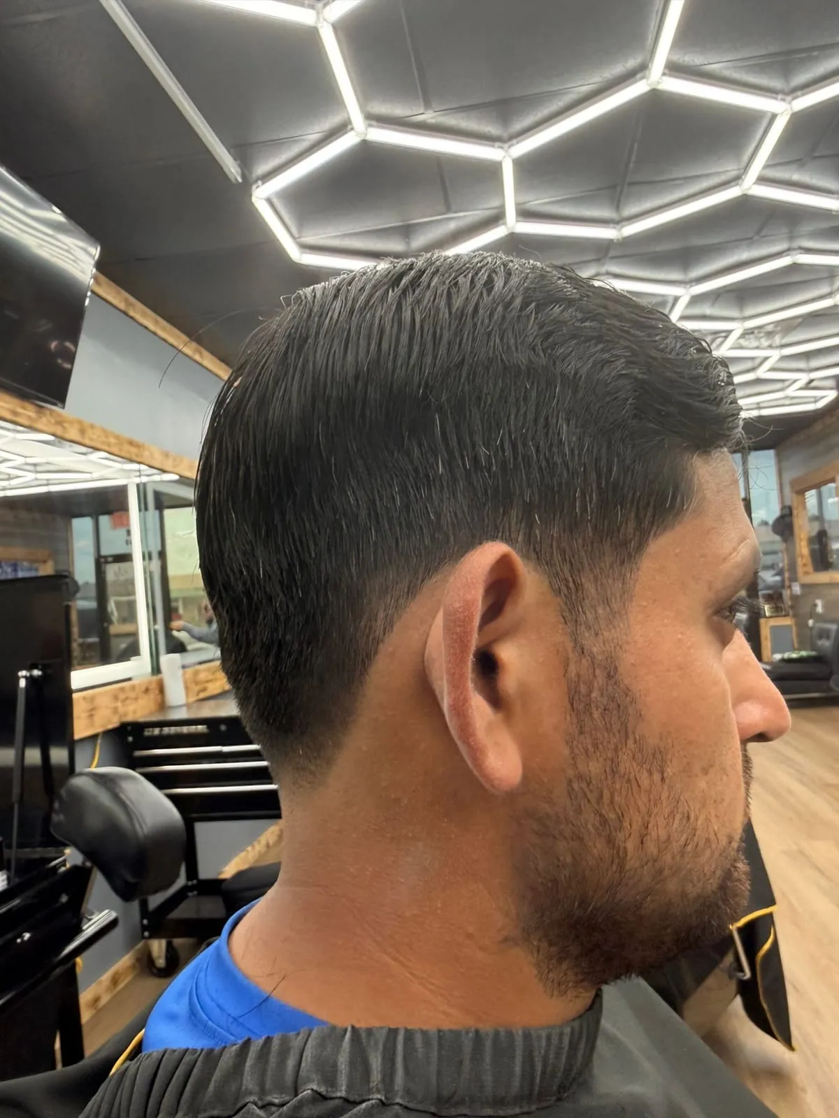 Man in profile with a short slicked top, a smooth taper and a neatly trimmed beard